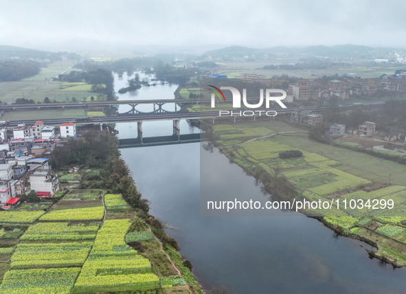 Fields of rapeseed flowers are blooming and mingling with villages, rivers, distant mountains, and roads in Yongzhou, Hunan Province, China,...