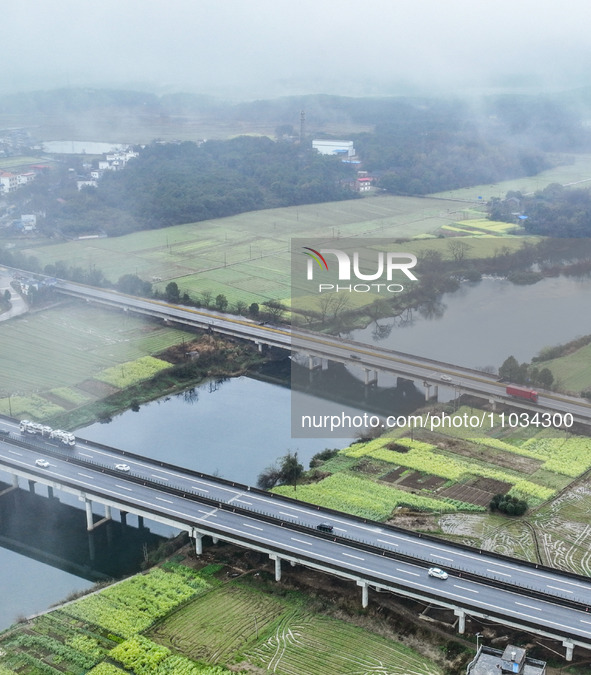 Fields of rapeseed flowers are blooming and mingling with villages, rivers, distant mountains, and roads in Yongzhou, Hunan Province, China,...