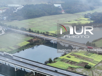 Fields of rapeseed flowers are blooming and mingling with villages, rivers, distant mountains, and roads in Yongzhou, Hunan Province, China,...