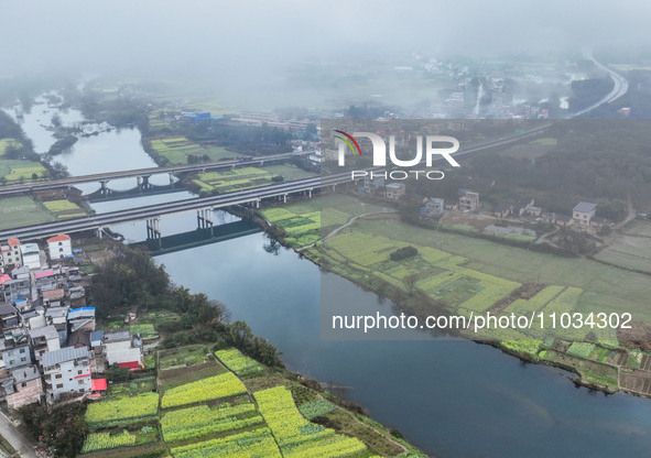 Fields of rapeseed flowers are blooming and mingling with villages, rivers, distant mountains, and roads in Yongzhou, Hunan Province, China,...