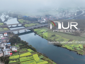 Fields of rapeseed flowers are blooming and mingling with villages, rivers, distant mountains, and roads in Yongzhou, Hunan Province, China,...