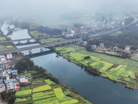 Fields of rapeseed flowers are blooming and mingling with villages, rivers, distant mountains, and roads in Yongzhou, Hunan Province, China,...