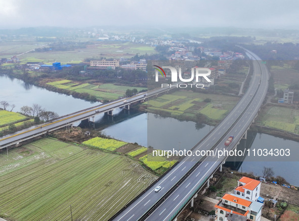 Fields of rapeseed flowers are blooming and mingling with villages, rivers, distant mountains, and roads in Yongzhou, Hunan Province, China,...