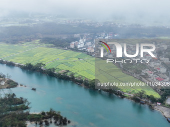 Fields of rapeseed flowers are blooming and mingling with villages, rivers, distant mountains, and roads in Yongzhou, Hunan Province, China,...