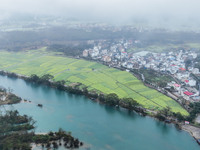 Fields of rapeseed flowers are blooming and mingling with villages, rivers, distant mountains, and roads in Yongzhou, Hunan Province, China,...