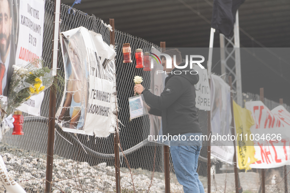 A relative of a 20-year-old woman who was fatally struck by a train is leaving a white rose on the wire fence beside the tracks, in Tempi Th...