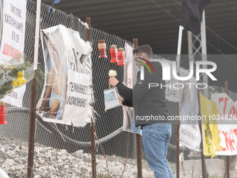 A relative of a 20-year-old woman who was fatally struck by a train is leaving a white rose on the wire fence beside the tracks, in Tempi Th...