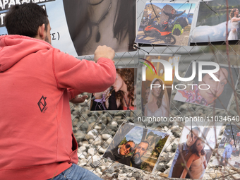 The husband of a young woman who was killed in a crash is hanging photos of her on the rail fence, in Tempi Thessaly, Greece, on on February...