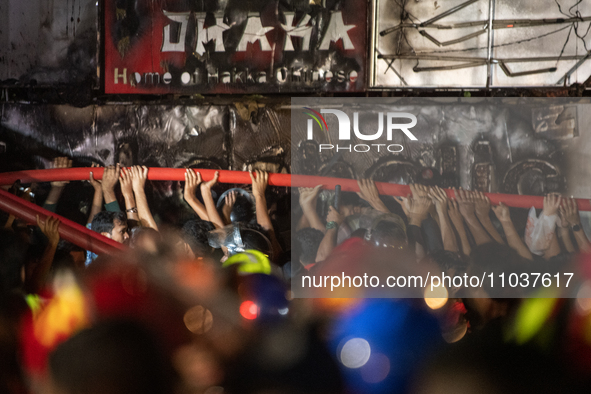 Volunteers are holding a water pipe after a fire in a multi-storey building in Dhaka, Bangladesh, on February 29, 2024. At least 43 people h...