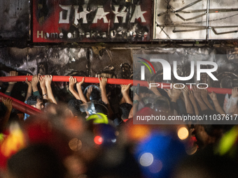 Volunteers are holding a water pipe after a fire in a multi-storey building in Dhaka, Bangladesh, on February 29, 2024. At least 43 people h...