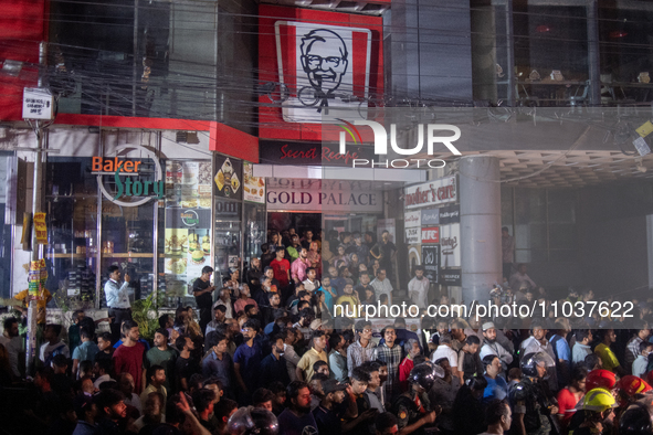 Curious onlookers are gathering at the site of a fire in a multi-storey building in Dhaka, Bangladesh, on February 29, 2024. At least 43 peo...