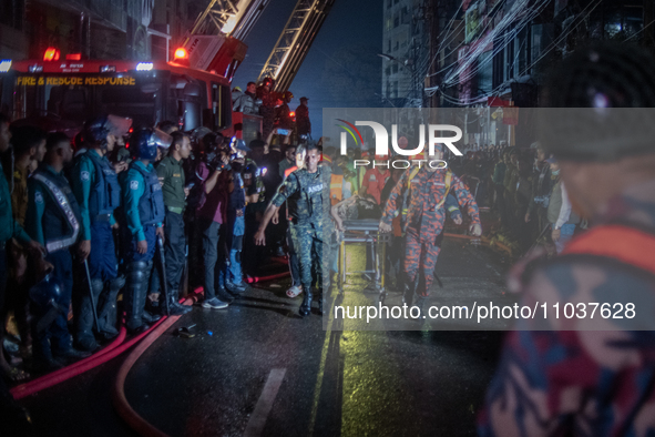 Firefighters are carrying an injured person during a rescue operation after a fire broke out in a commercial building in Dhaka, Bangladesh,...