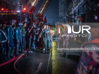 Firefighters are carrying an injured person during a rescue operation after a fire broke out in a commercial building in Dhaka, Bangladesh,...