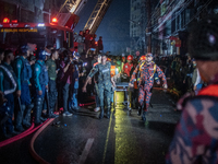 Firefighters are carrying an injured person during a rescue operation after a fire broke out in a commercial building in Dhaka, Bangladesh,...