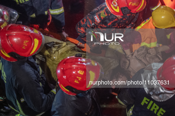 Firefighters are carrying an injured person during a rescue operation after a fire broke out in a commercial building in Dhaka, Bangladesh,...