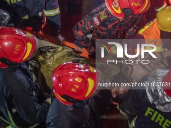 Firefighters are carrying an injured person during a rescue operation after a fire broke out in a commercial building in Dhaka, Bangladesh,...