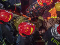 Firefighters are carrying an injured person during a rescue operation after a fire broke out in a commercial building in Dhaka, Bangladesh,...