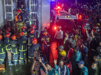 Firefighters are carrying an injured person during a rescue operation after a fire broke out in a commercial building in Dhaka, Bangladesh,...