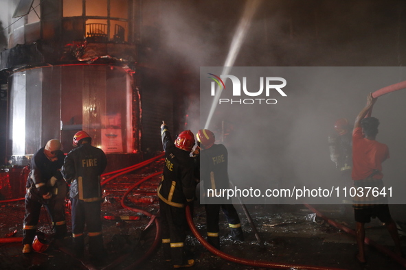 Firefighters are working to extinguish a fire in a commercial building that has killed at least 43 people in Dhaka, Bangladesh, on February...