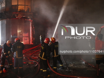 Firefighters are working to extinguish a fire in a commercial building that has killed at least 43 people in Dhaka, Bangladesh, on February...