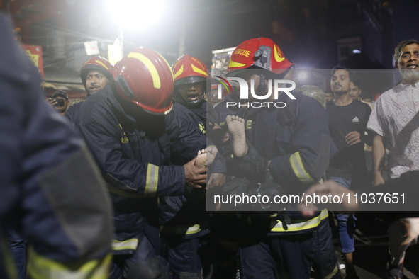 Firefighters are carrying an injured person during rescue operations following a fire in a commercial building that has killed at least 43 p...