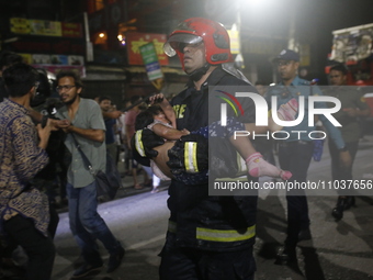 A firefighter is carrying an injured person during rescue operations following a fire in a commercial building in Dhaka, Bangladesh, on Febr...