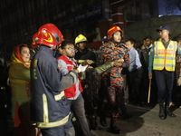 Firefighters are carrying an injured person during rescue operations following a fire in a commercial building that has killed at least 43 p...