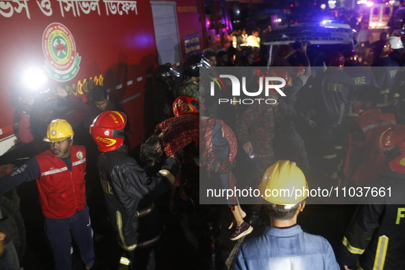 Firefighters are carrying an injured person during rescue operations following a fire in a commercial building that has killed at least 43 p...