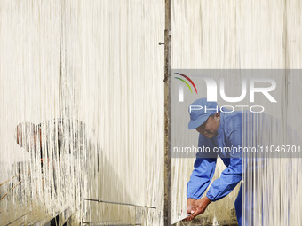 A worker is processing hollow hanging noodles at a workshop in Suqian, Jiangsu Province, China, on March 3, 2024. (