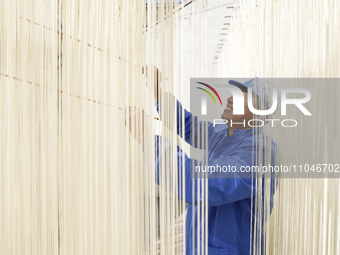 A worker is processing hollow hanging noodles at a workshop in Suqian, Jiangsu Province, China, on March 3, 2024. (