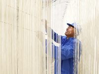 A worker is processing hollow hanging noodles at a workshop in Suqian, Jiangsu Province, China, on March 3, 2024. (