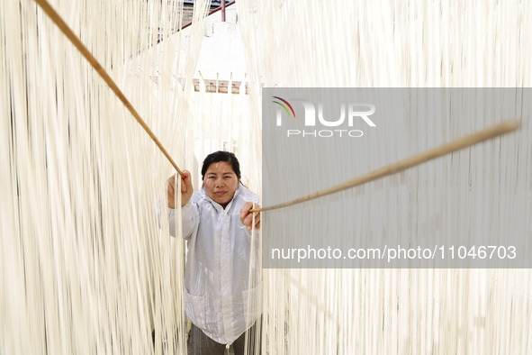 A worker is processing hollow hanging noodles at a workshop in Suqian, Jiangsu Province, China, on March 3, 2024. 