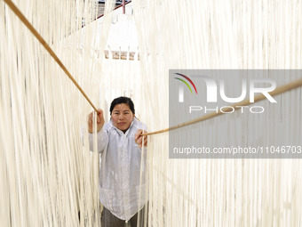 A worker is processing hollow hanging noodles at a workshop in Suqian, Jiangsu Province, China, on March 3, 2024. (