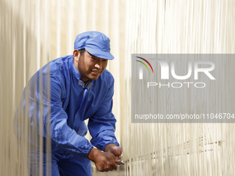 A worker is processing hollow hanging noodles at a workshop in Suqian, Jiangsu Province, China, on March 3, 2024. (