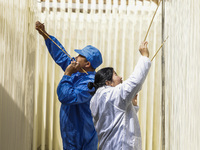 Two workers are processing hollow hanging noodles at a workshop in Suqian, Jiangsu Province, China, on March 3, 2024. (