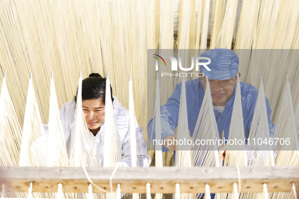 Two workers are processing hollow hanging noodles at a workshop in Suqian, Jiangsu Province, China, on March 3, 2024. 