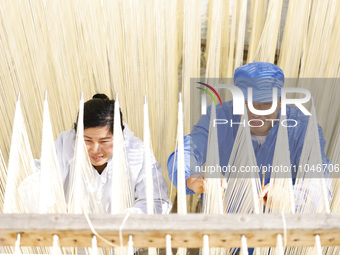 Two workers are processing hollow hanging noodles at a workshop in Suqian, Jiangsu Province, China, on March 3, 2024. (