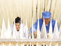 Two workers are processing hollow hanging noodles at a workshop in Suqian, Jiangsu Province, China, on March 3, 2024. (