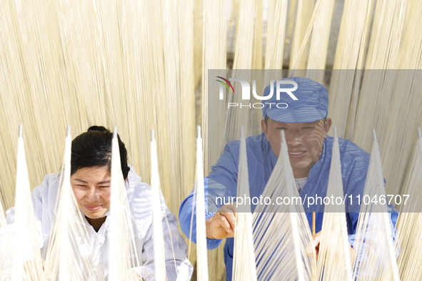 Two workers are processing hollow hanging noodles at a workshop in Suqian, Jiangsu Province, China, on March 3, 2024. 