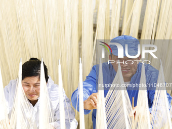 Two workers are processing hollow hanging noodles at a workshop in Suqian, Jiangsu Province, China, on March 3, 2024. (