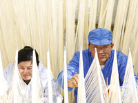 Two workers are processing hollow hanging noodles at a workshop in Suqian, Jiangsu Province, China, on March 3, 2024. (