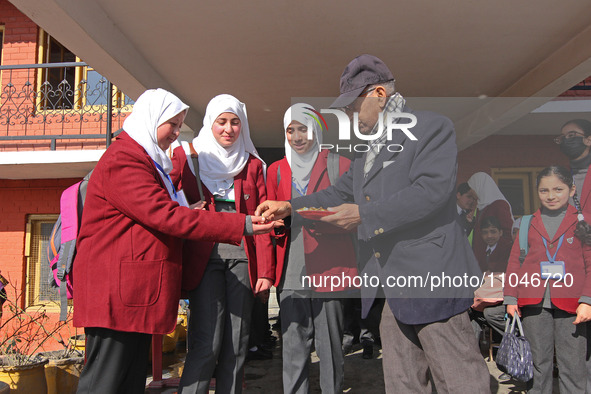 The school principal is distributing candies among students on the first day in Srinagar, India, on March 4, 2024. Schools across Kashmir ar...