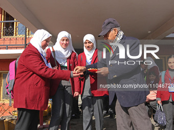 The school principal is distributing candies among students on the first day in Srinagar, India, on March 4, 2024. Schools across Kashmir ar...