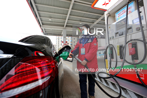 A worker is filling up a car at a gas station in Lianyungang, China, on March 4, 2024. 