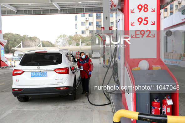 A worker is filling up a car at a gas station in Lianyungang, China, on March 4, 2024. 