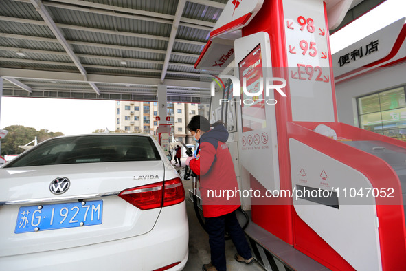 A worker is filling up a car at a gas station in Lianyungang, China, on March 4, 2024. 