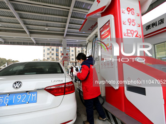 A worker is filling up a car at a gas station in Lianyungang, China, on March 4, 2024. (