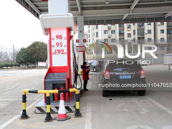 A worker is filling up a car at a gas station in Lianyungang, China, on March 4, 2024. (