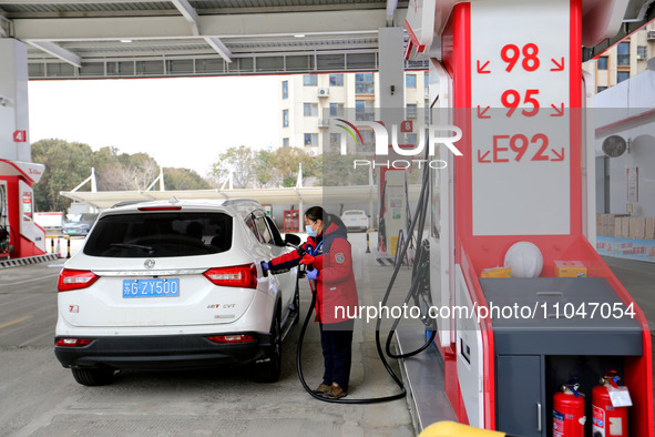 A worker is filling up a car at a gas station in Lianyungang, China, on March 4, 2024. 