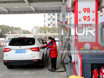 A worker is filling up a car at a gas station in Lianyungang, China, on March 4, 2024. (